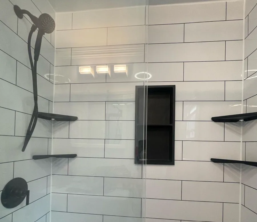Modern walk-in shower with white subway tile, black fixtures, and built-in recessed shelf in bathroom